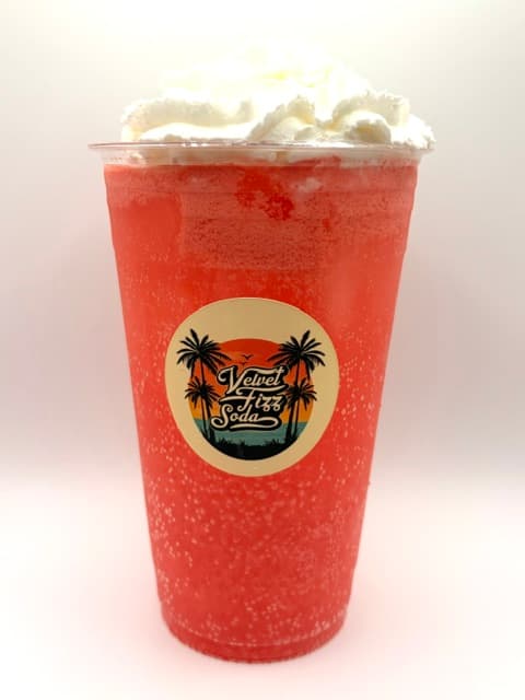 Bright red fizzy drink with whipped cream in a cup featuring Velvet Fizz Soda logo.